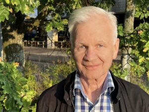 Reijo Laitinen, kasvokuva, taustalla puun vihreitä lehtiä