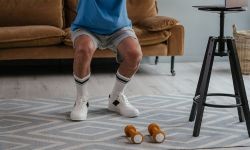Ikämies jumppaa olohuoneessaan