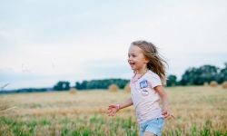 Tyttö jouksee iloisena pellolla