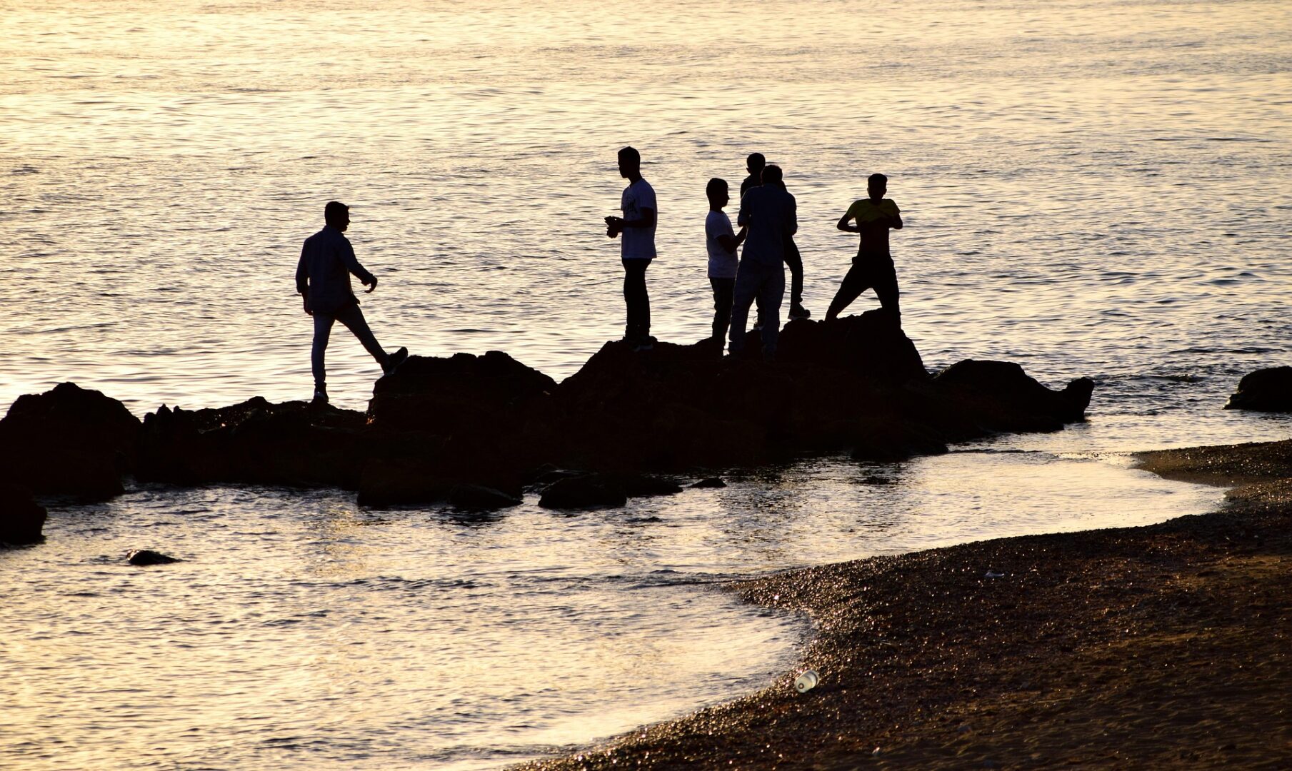 Nuoret rantakalliolla auringonlaskun aikaan