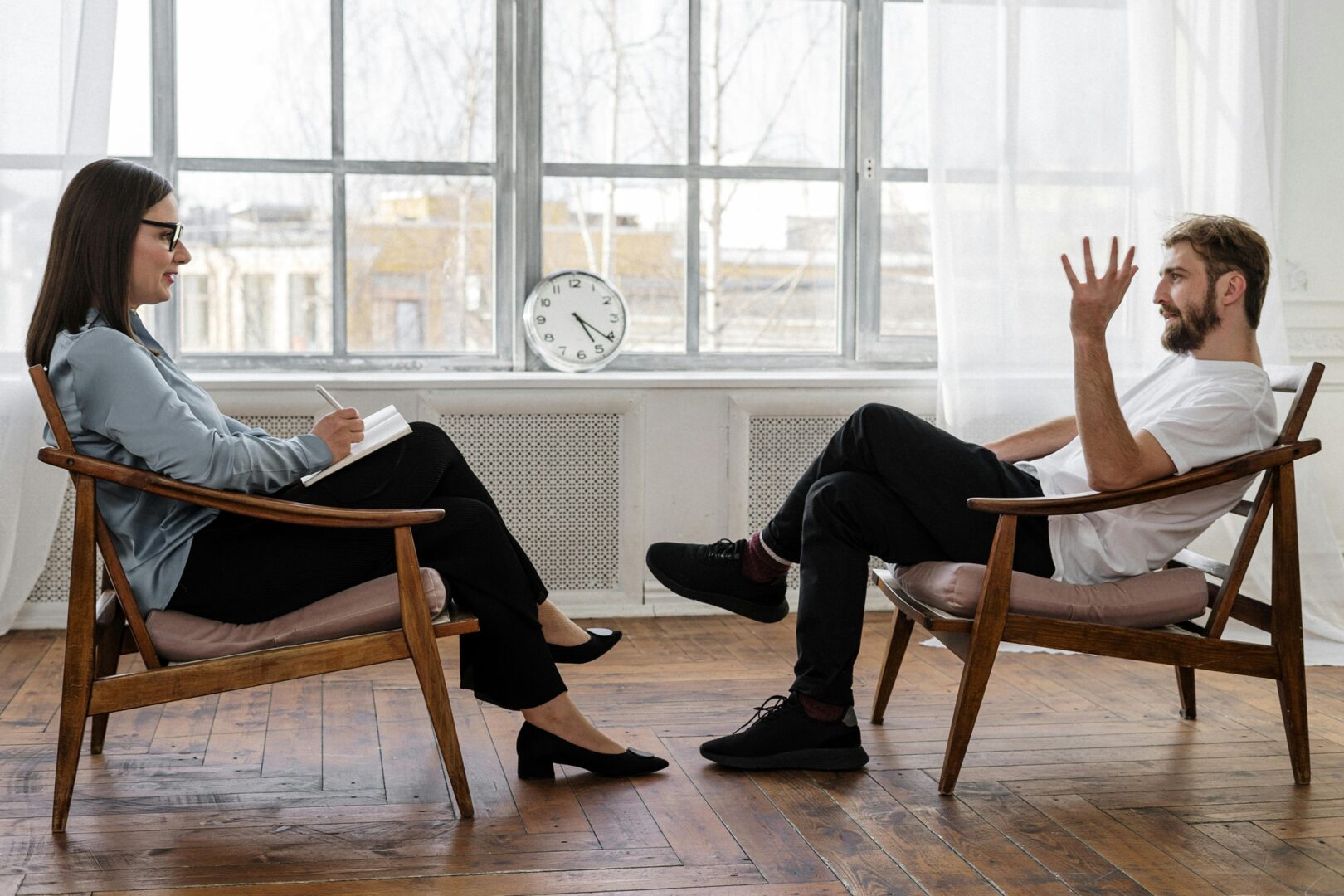 Mies ja nainen istuvat vastakkain ja keskustelevat